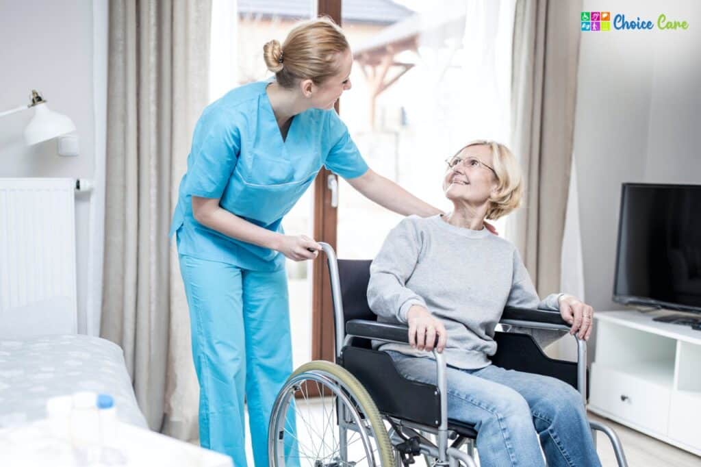 Caregiver assisting a smiling elderly woman in a wheelchair at home, providing accommodation and tenancy assistance support services.