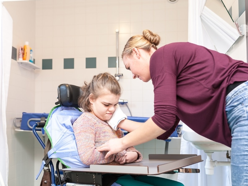 A support worker assisting a young woman in a wheelchair, highlighting support coordination funding in daily activities.