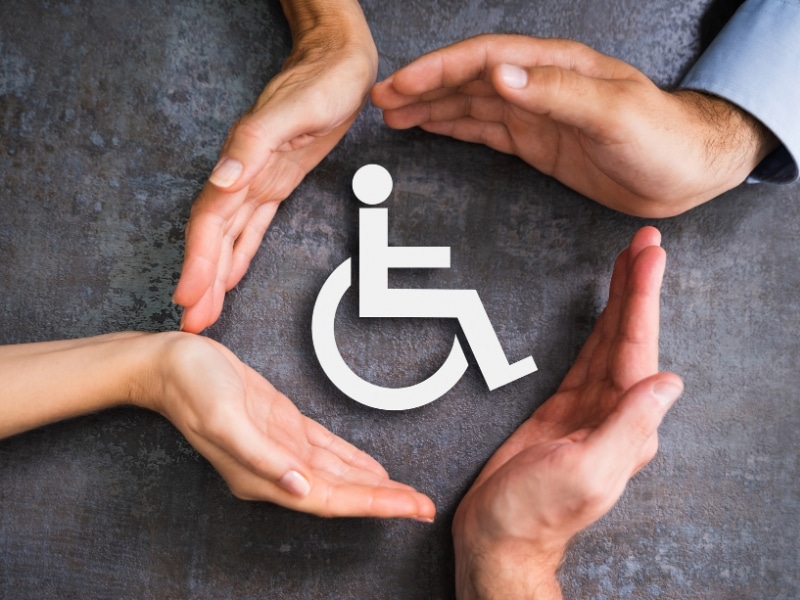 Hands forming a circle around a disability symbol - representing disability help and support.