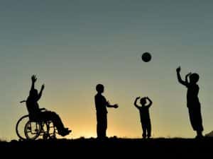 Silhouette of children playing, one in a wheelchair - Inclusive play supported by NDIS personal activities funding.