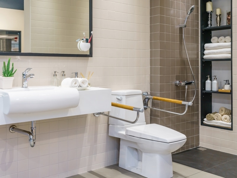 A safe and accessible bathroom with grab rails and a raised toilet seat, promoting independence for people with disabilities.