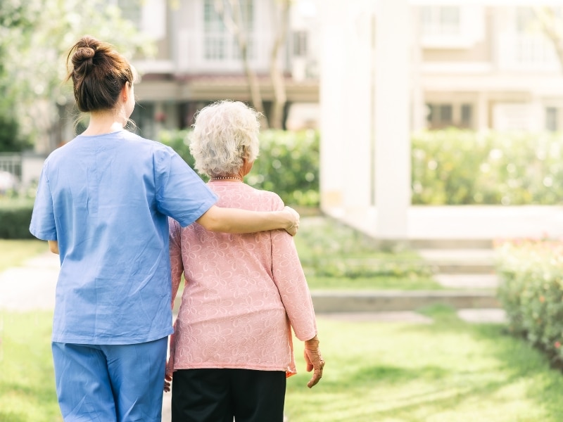 Caregiver offering assistance with self care activities to an elderly woman, showing a supportive and caring relationship.