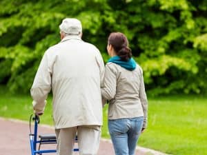 Caregiver providing assistance with self care activities, helping an elderly man walk safely and comfortably