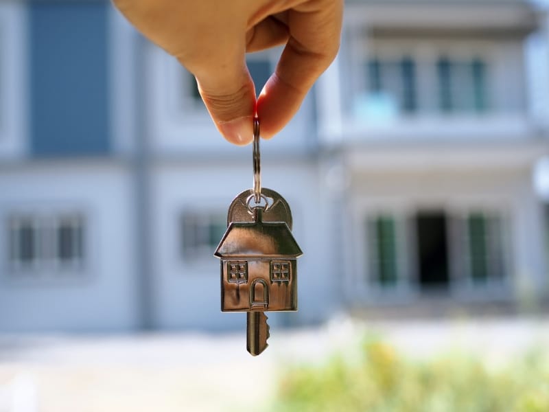 A hand holds a house-shaped key ring, symbolizing supported tenancy and the opportunity for safe and stable housing.